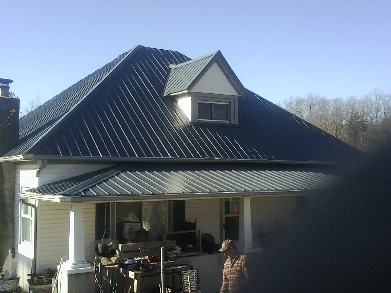 Dark blue standing seam metal roof with a dormer above a front porch in Gainesville